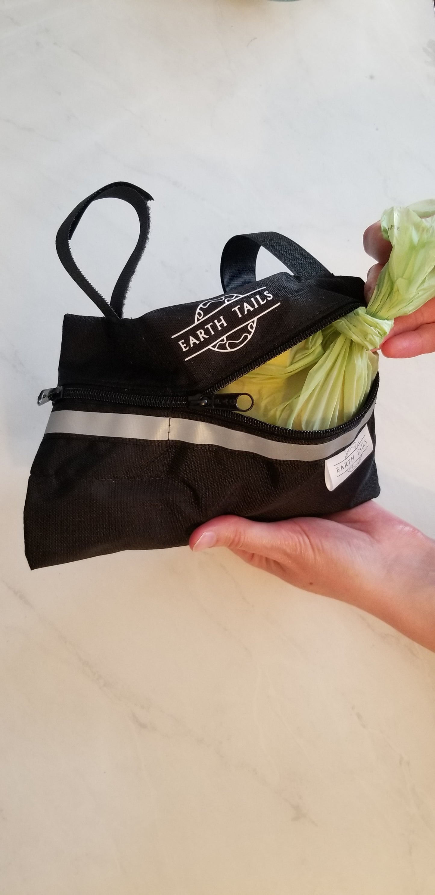 The Lil' Roller bag being filled with a full dog waste bag to illustrate the amount of waste which can be held. For context, 4 medium-sized banana peels fit into the Lil' Roller bag.